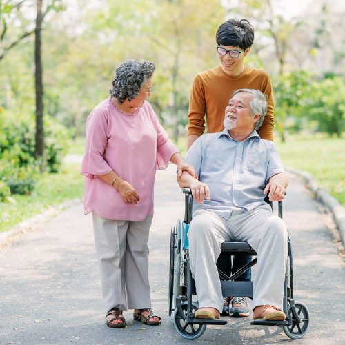 Senior Asian man in wheelchair with his wife and son