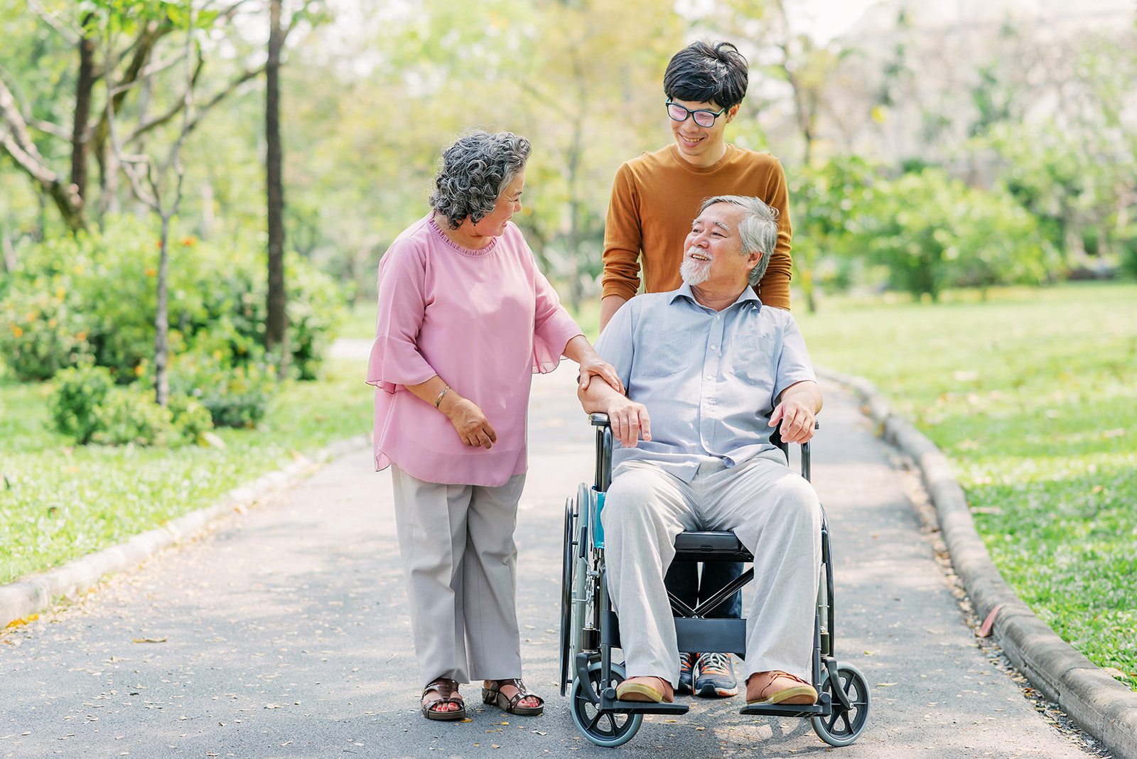 Senior Asian man in wheelchair with his wife and son
