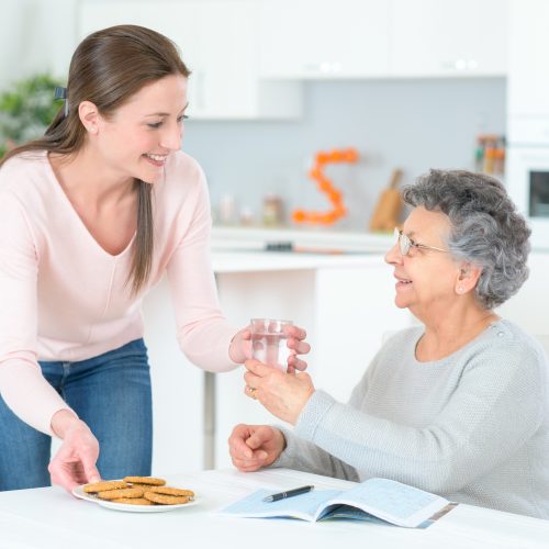 woman handing an older adult a glass of water